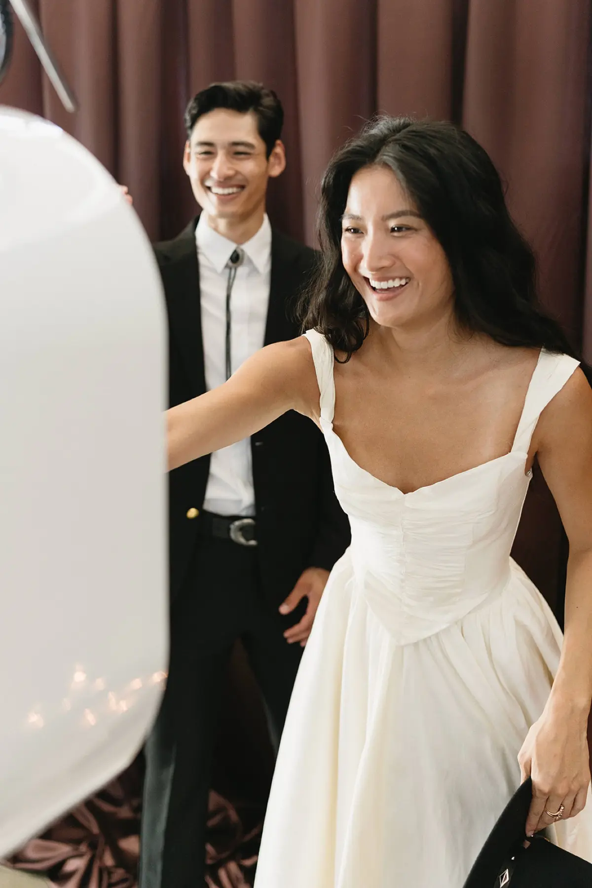 Guests posing at a western-themed photo booth with a rustic brown curtain backdrop at a corporate event